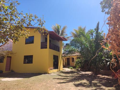 una casa amarilla con árboles delante de ella en Chalé da Selma I (Isaías) en Alto Paraíso de Goiás