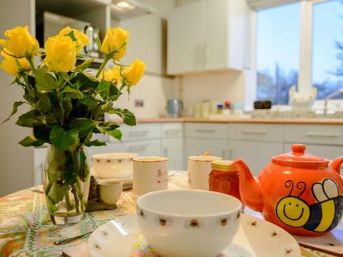 een tafel met een vaas van gele rozen en een vaas van een thee bij 2 Bed in Whitstable 90344 in Whitstable