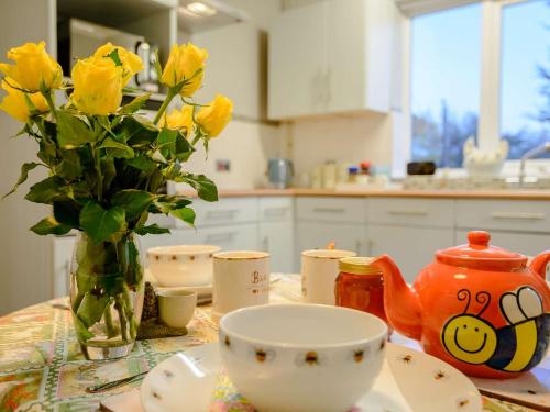 a table with a vase of yellow roses and a vase of a tea at 2 Bed in Whitstable 90344 in Whitstable