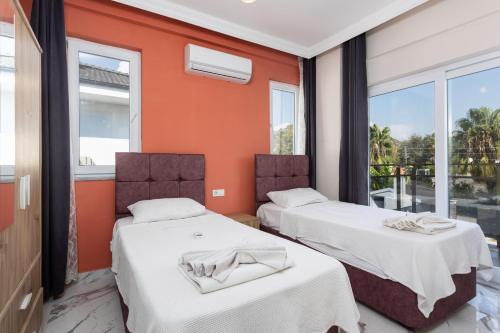 two beds in a room with orange walls and windows at Villa Mazoya in Dalyan