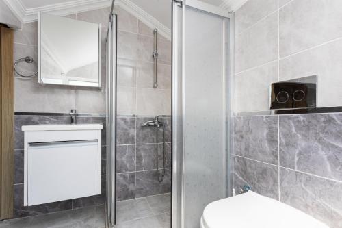 uma casa de banho com um chuveiro, um WC e um espelho. em Villa Mazoya em Dalyan