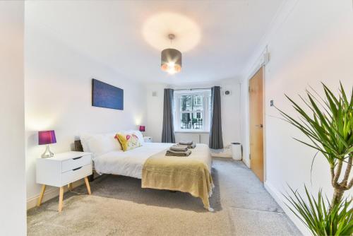 a white bedroom with a bed and a plant at Fantastic Central Line City-pad! in London