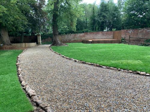 a gravel path in a garden with a grass yard at Apartment Two, The Carriage House, Bilbrough, York in York