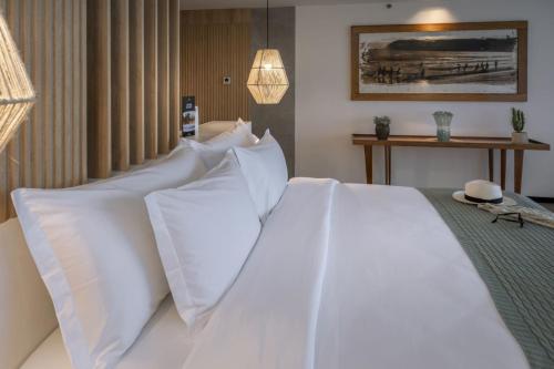 a white bed with white pillows in a bedroom at SERHS Experience Suítes in Natal