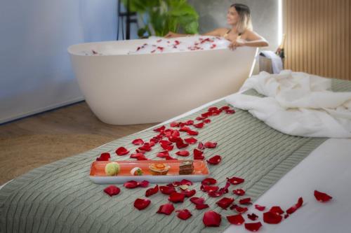 a woman taking a bath in a bath tub with red roses at SERHS Experience Suítes in Natal