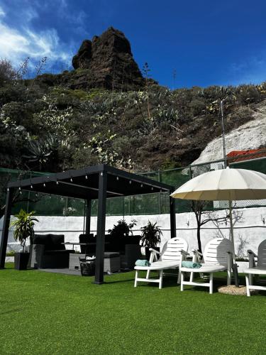 eine Gruppe von Stühlen und Sonnenschirmen auf dem Rasen in der Unterkunft Encantadora Casa cueva en Valsequillo in Las Palmas de Gran Canaria