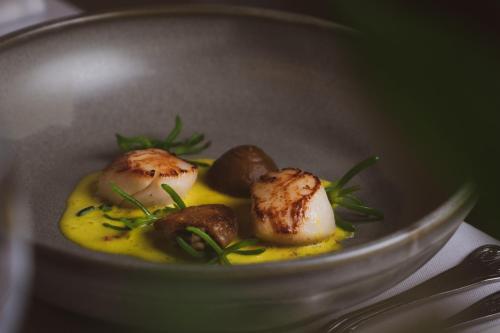 a plate of food with mushrooms on a yellow sauce at Briery Wood Hotel in Ambleside