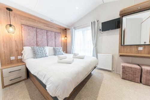ein Schlafzimmer mit einem großen Bett und einem Fernseher an der Wand in der Unterkunft Tastefully decorated lodge on popular holiday park, easy access to Lakes and Dales and free parking in Carnforth