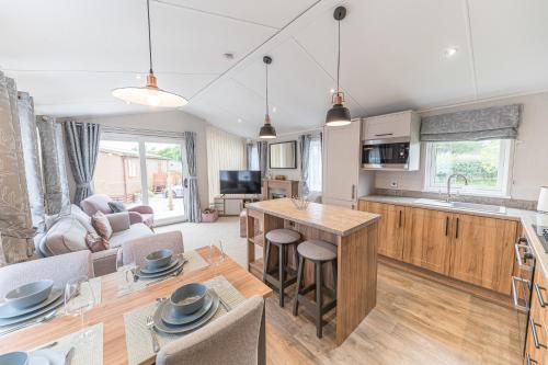 a kitchen and living room with a table and a couch at Tastefully decorated lodge on popular holiday park, easy access to Lakes and Dales and free parking in Carnforth