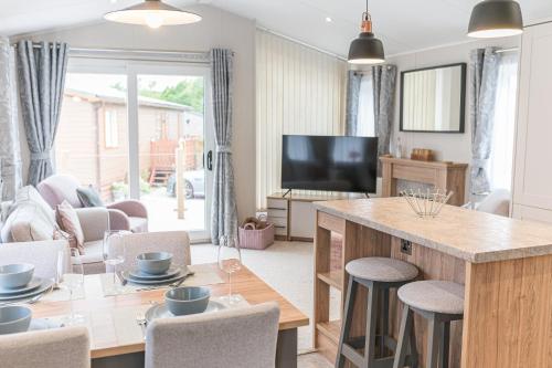a kitchen and living room with a table and a television at Tastefully decorated lodge on popular holiday park, easy access to Lakes and Dales and free parking in Carnforth