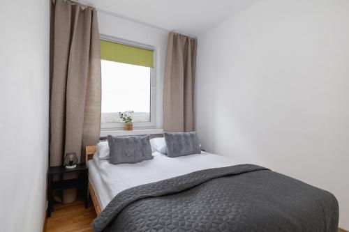 a bedroom with a bed with two pillows and a window at Close to Railway Station Apartment on the 7th Floor in Katowice by Renters in Katowice