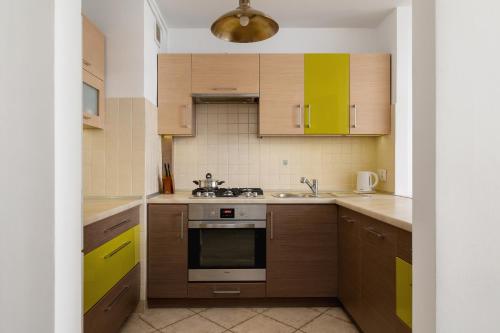 a kitchen with wooden cabinets and a stove top oven at Close to Railway Station Apartment on the 7th Floor in Katowice by Renters in Katowice