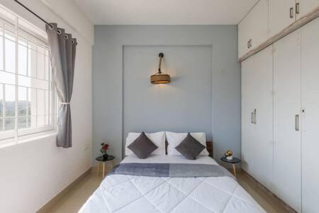 - une chambre blanche dotée d'un lit avec oreillers et d'une fenêtre dans l'établissement Blue Pearl Apartment by JadeCaps Nr Airport 3bhk, à Devanhalli