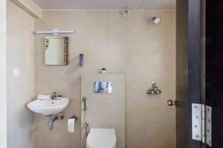 La salle de bains est pourvue de toilettes et d'un lavabo. dans l'établissement Blue Pearl Apartment by JadeCaps Nr Airport 3bhk, à Devanhalli
