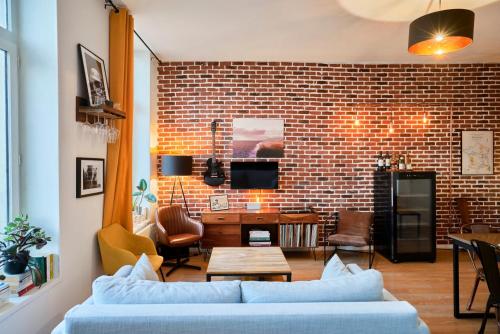 un salon avec un canapé et un mur de briques dans l'établissement 1 bedroom apartment near metro, shops & schools, à Lille