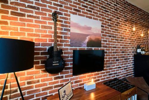 - un mur en briques avec une télévision et une guitare dans l'établissement 1 bedroom apartment near metro, shops & schools, à Lille