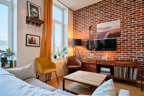 un salon avec un canapé et un mur de briques dans l'établissement 1 bedroom apartment near metro, shops & schools, à Lille