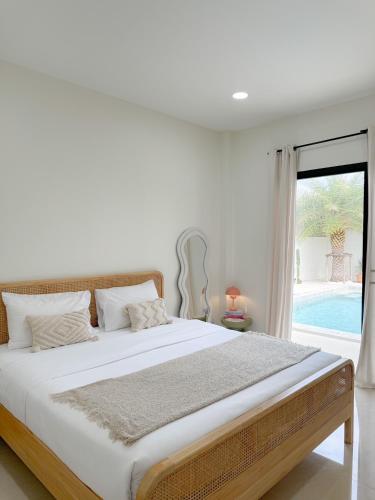 a white bedroom with a large bed and a window at Villa all day Pool Villa Hat Chao Samran หาดเจ้าสำราญ in Haad Chao Samran