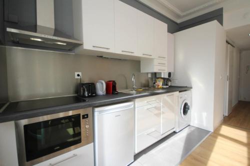 une cuisine avec des armoires blanches et une laveuse et une sécheuse dans l'établissement Fully-equipped apartment in city center + parking, à Lille