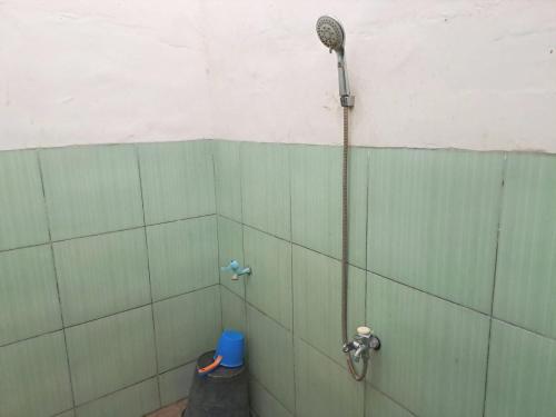 La salle de bains est pourvue d'une douche et d'un mur carrelé vert. dans l'établissement OYO 93590 Penginapan Palapa 10 Syariah, à Bandar Lampung