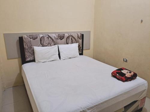 - un lit avec des draps blancs et une tête de lit dans la chambre dans l'établissement OYO 93590 Penginapan Palapa 10 Syariah, à Bandar Lampung