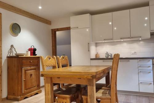 a kitchen with a wooden table and some chairs at Un séjour plein de charme aux Posses! in Gryon