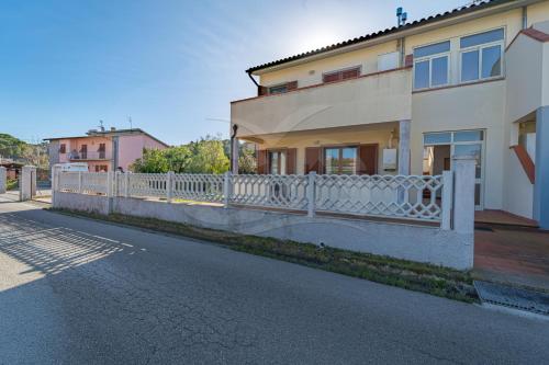 ein Haus mit einem weißen Zaun an der Straßenseite in der Unterkunft Appartamenti Rosa Campo Mare - Goelba in Marina di Campo