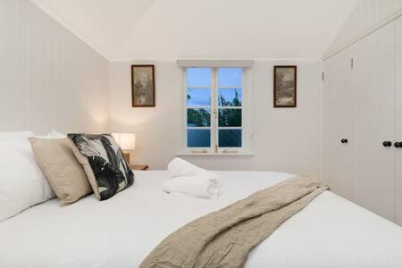 una camera bianca con un grande letto con finestra di The Indooroopilly Queenslander - 4 Bedroom Family Home - Private Pool - Wifi - Netflix a Brisbane