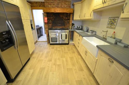 a kitchen with a stainless steel refrigerator and wooden floors at The Hive 4 Bed House Pool Table Air-con in Maidstone