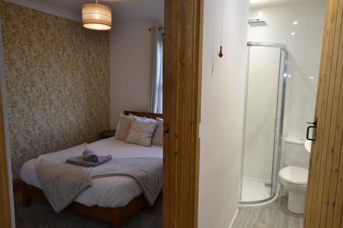 a bedroom with a bed and a bathroom with a shower at The Hive 4 Bed House Pool Table Air-con in Maidstone
