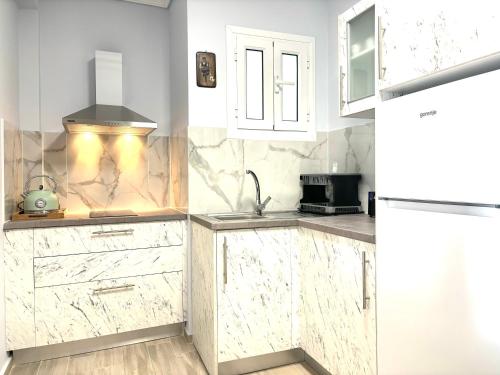 a kitchen with marble counter tops and white cabinets at Nelly's Luxury Suites in Kassiopi