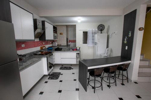 a kitchen with white cabinets and a black counter top at Sobrado com Piscina - Pontal do Parana in Pontal do Paraná