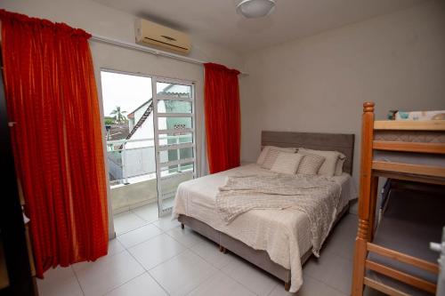 a bedroom with a bed with red curtains and a window at Sobrado com Piscina - Pontal do Parana in Pontal do Paraná