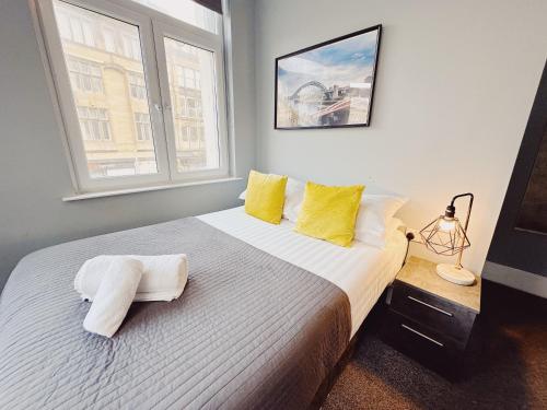 a bedroom with a bed with yellow pillows and a window at 3 Bedroom Apartment in the Heart of Newcastle - Modern - Sleeps 6 in Newcastle upon Tyne