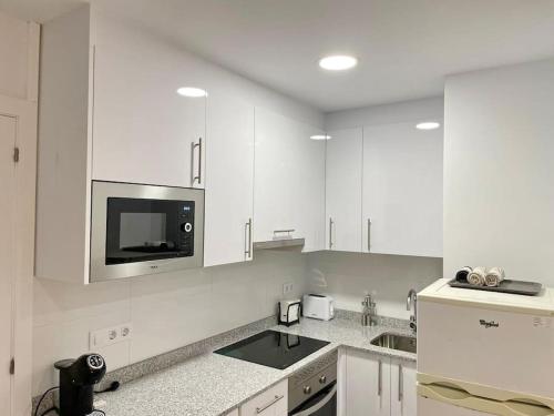 eine weiße Küche mit weißen Schränken und einer Mikrowelle in der Unterkunft Apartamento al lado de la playa in Barcelona