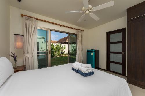 1 dormitorio con 1 cama, ventilador de techo y ventana en Villa Kaheru | 3 bedroom priavate pool villa | Kokyang Estate, en Nai Harn Beach