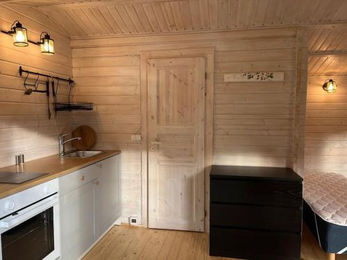 a kitchen with wooden walls and a bed in a room at Salu summer cottage in Vadi