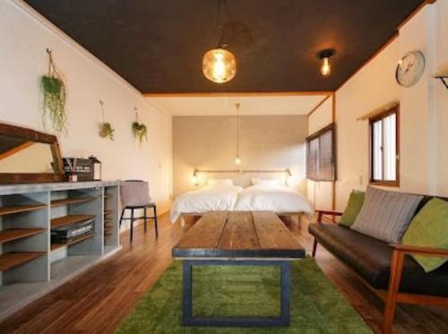 a bedroom with a bed and a couch and a table at ゲストハウス弓と糸 Guesthouse Yumi To Ito in Nagano