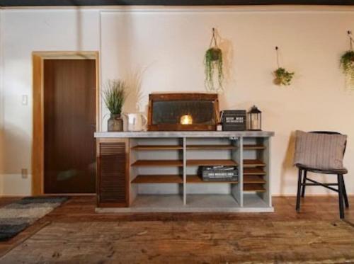 a desk with a microwave and a chair in a room at ゲストハウス弓と糸 Guesthouse Yumi To Ito in Nagano