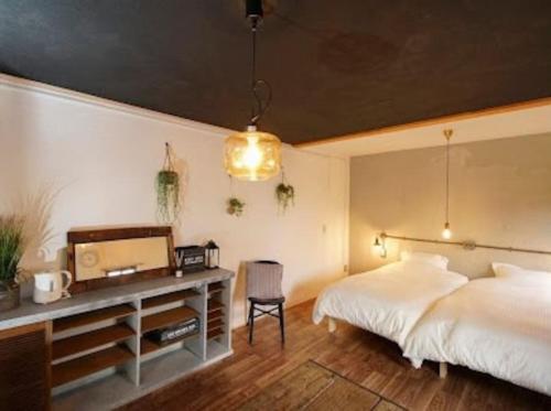 a bedroom with two beds and a desk with a tv at ゲストハウス弓と糸 Guesthouse Yumi To Ito in Nagano
