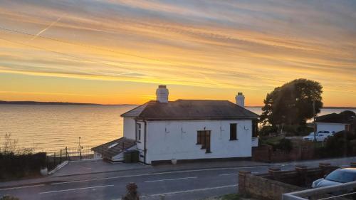 a small white house next to a body of water at The Patch in Hill Head