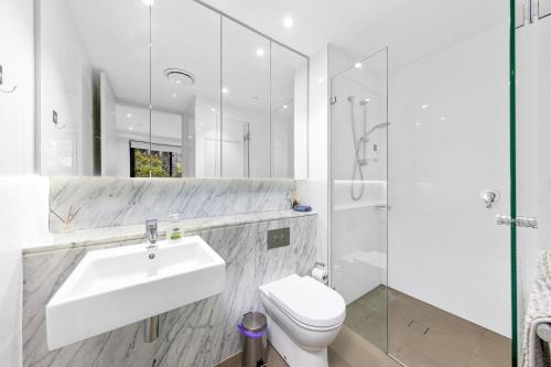 a white bathroom with a sink and a toilet at Super comfy 2B Apt in Burwood in Sydney