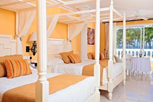 una camera con 2 letti arancioni e bianchi di Bahia Principe Luxury Bouganville - Adults Only All Inclusive a La Romana