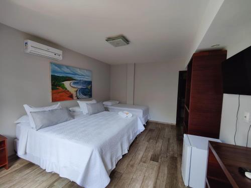 a bedroom with two beds and a flat screen tv at Pousada Waikiki Boutique in Pipa