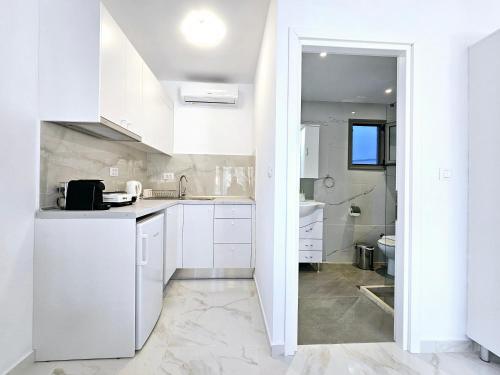 a white kitchen with white cabinets and a sink at Dream Luxury Suites & Apartment in Pastida