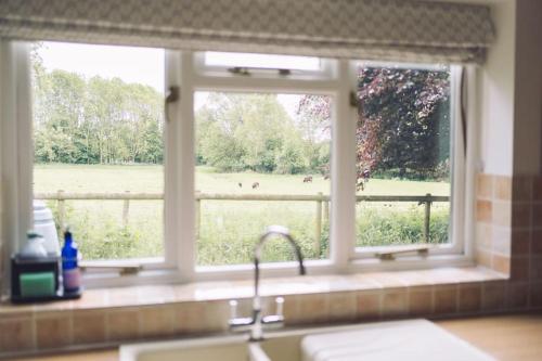uma janela de cozinha com vista para um campo em Detached homely bungalow with open fireplace em Priors Marston