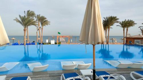 Villa with private pool cancun elsokhna 93 في العين السخنة: مسبح كبير مع كراسي و نخيل