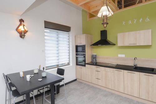 een keuken met een zwarte tafel en een keuken met groene muren bij GITE MELODIE + Sauna Extérieur in Gosnay