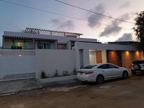 a white car parked in front of a house at Flats Marina Maragogi in Maragogi