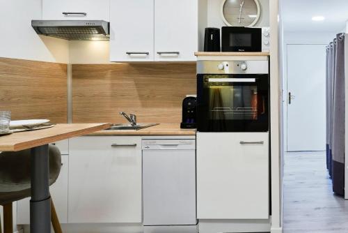 a kitchen with white cabinets and a stove top oven at Large studio between train station & Grand Place in Lille